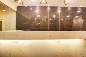 A modern bathroom with a marble countertop, a large mirror, and recessed lighting. - RCC Hotels Banjara Hills (Hyderabad)