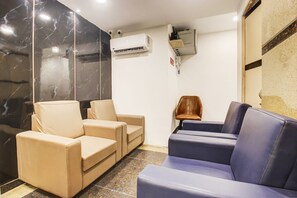 A room with beige and blue seating, a wall-mounted air conditioner, and a security camera. - RCC Hotels Banjara Hills (Hyderabad)