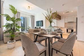 A modern living room with a dining area, large windows, and a kitchen. - High-Floor 2BR with Balcony Framing Stunning Burj Khalifa Views,Near Dubai Mall (Dubai)