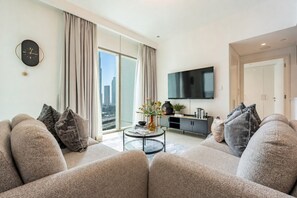 A modern living room with a sofa set, a coffee table, and a flat-screen TV mounted on the wall. - High-Floor 2BR with Balcony Framing Stunning Burj Khalifa Views,Near Dubai Mall (Dubai)