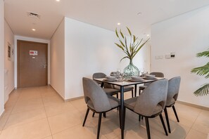 A dining area with a table set for four, surrounded by grey upholstered chairs. - High-Floor 2BR with Balcony Framing Stunning Burj Khalifa Views,Near Dubai Mall (Dubai)