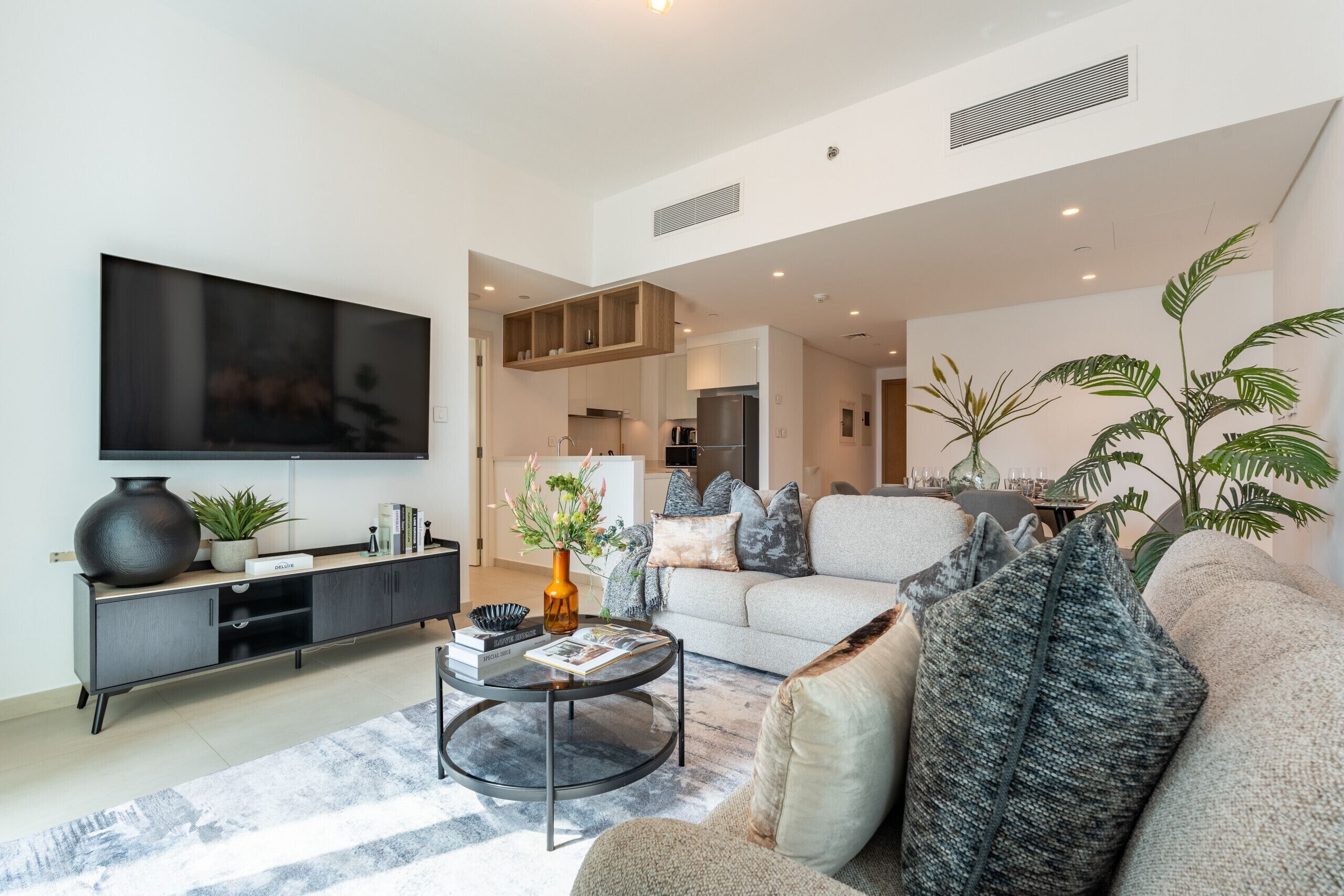 Ein modernes Wohnzimmer mit Fernseher, Couchtisch mit Zeitschriften, Sofa und Bücherregal.