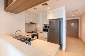 A modern kitchen with a stainless steel refrigerator, a built-in oven, and a microwave. - High-Floor 2BR with Balcony Framing Stunning Burj Khalifa Views,Near Dubai Mall (Dubai)