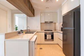 A modern kitchen with a built-in oven, a stainless steel refrigerator, and a gas stove. - High-Floor 2BR with Balcony Framing Stunning Burj Khalifa Views,Near Dubai Mall (Dubai)