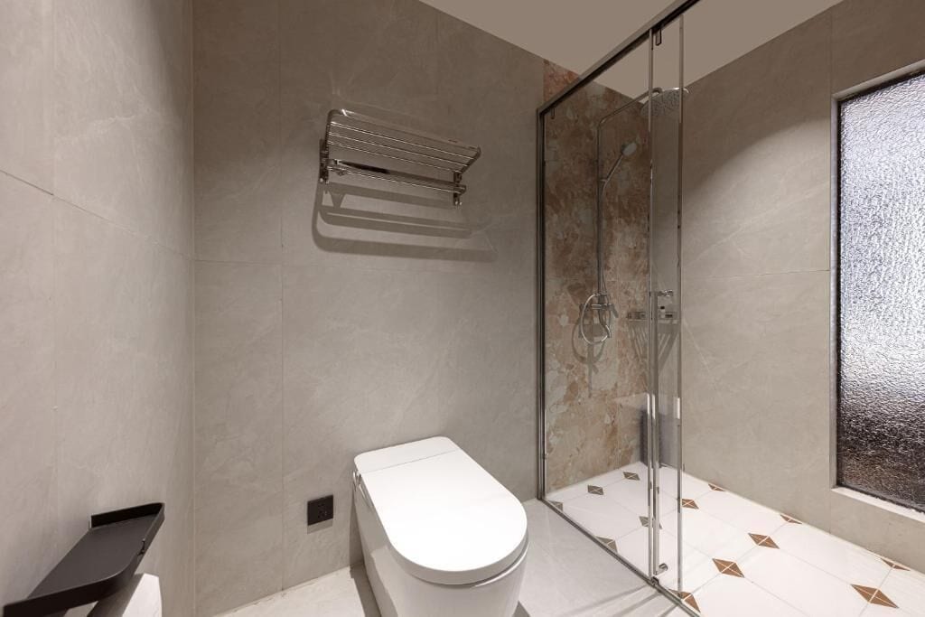 A modern bathroom with a toilet, a glass shower enclosure, and a towel rack.