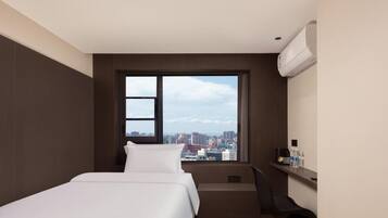 Una habitación de hotel moderna con un ventanal grande, una cama, un escritorio y una silla.