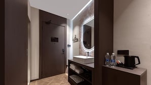 A modern bathroom with a large mirror, a sink, and a vanity with toiletries.