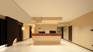 A modern hotel lobby with a reception desk, a flat floor, and a ceiling with recessed lighting.