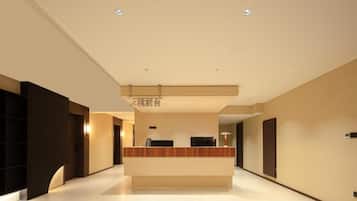 A modern hotel lobby with a reception desk, a flat floor, and a ceiling with recessed lighting.