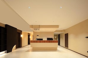 A modern hotel lobby with a reception desk, a flat floor, and a ceiling with recessed lighting. - Mutao Hotel Hubin in 77 (Hang Zhou Shi)