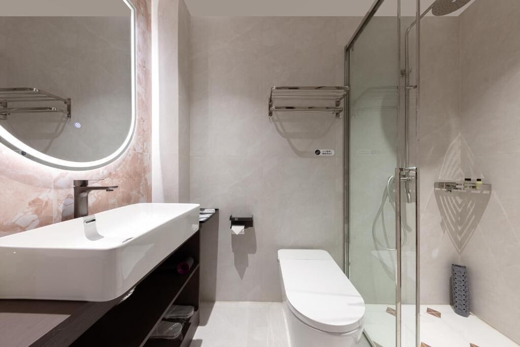 Un baño moderno con un lavabo blanco, un inodoro y un box de ducha de vidrio.