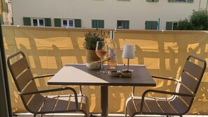 En utomhusplats med ett bord och stolar, en krukväxt, en flaska och ett glas.