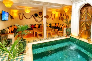 Area piscina con zona relax, una porta in legno con un cartello e decorazioni murali.
