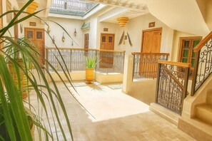 A hotel corridor with a staircase, wooden doors, and a potted plant. - Agafay, Riad Belikoss Pool & SPA (Marrakech)