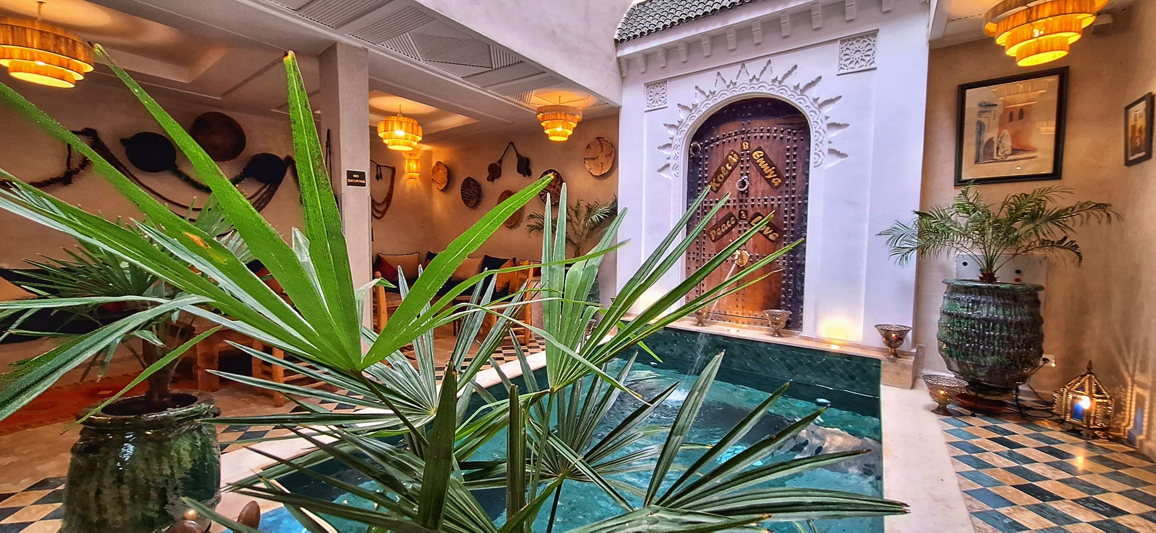 A pool area with a checkered floor, surrounded by potted plants and a decorative door.
