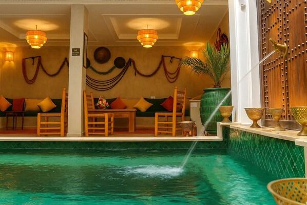 Area piscina con un angolo relax, elementi decorativi e una fontana.