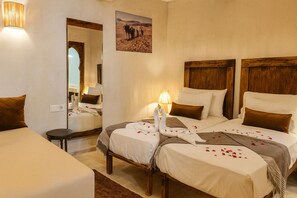 Una camera d'albergo con due letti, uno specchio, un quadro e una lampada.