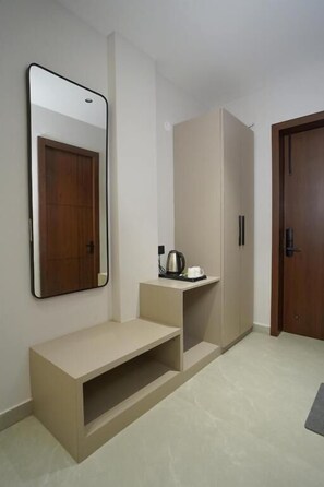 Un pasillo con un banco, un espejo, un armario y una puerta.