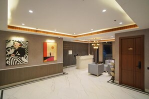 Un vestíbulo de hotel con mostrador de recepción, zona de estar y obras de arte en las paredes.