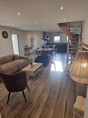 Ein modernes Wohnzimmer mit Sofa, Couchtisch und Essbereich.