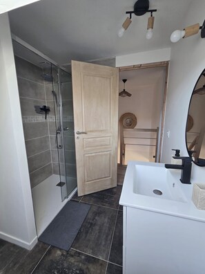 Ein modernes Badezimmer mit Dusche, Waschbecken und Spiegel.