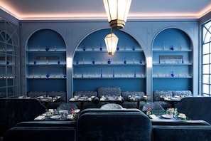 A dining area with blue walls, arched shelves, and a central light fixture. Tables are set with plates, glasses, and cutlery. - Palazzo Sogni (Florence)