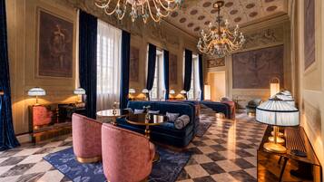 Um hall luxuoso com piso xadrez, sofás elegantes e lustres.
