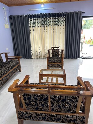 A room with a wooden sofa, a wooden chair, and a patterned bed.