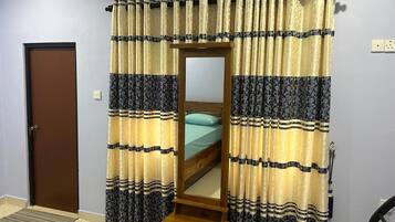 A bedroom with a bed, a wooden nightstand, a mirror, and curtains with a striped pattern.