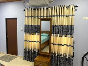 A bedroom with a bed, a wooden nightstand, a mirror, and curtains with a striped pattern. - Large, Peaceful 5‑Bedroom Home Just Steps from Jaffna Town (Jaffna)
