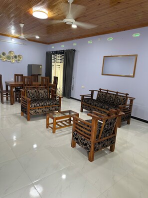 A room with a dining table, chairs, a sofa set, a ceiling fan, and recessed lighting.