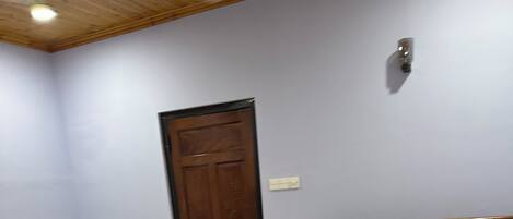 A bedroom with a large bed, a smaller bed, a wooden door, and a tiled floor.