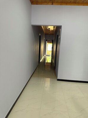 A hallway with a tiled floor leading to an open area.