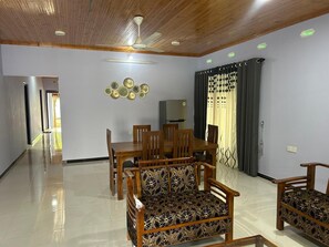 A spacious living area with a dining table, chairs, and a sofa.