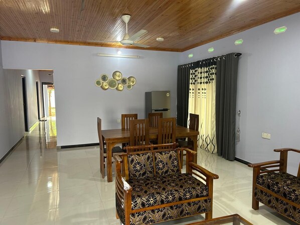 A spacious living area with a dining table, chairs, and a sofa.