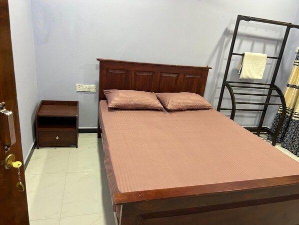 A bedroom with a wooden bed, a nightstand, and a metal shelf unit.