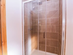 Eine Duschkabine mit Handbrause und Armaturen an der Wand.