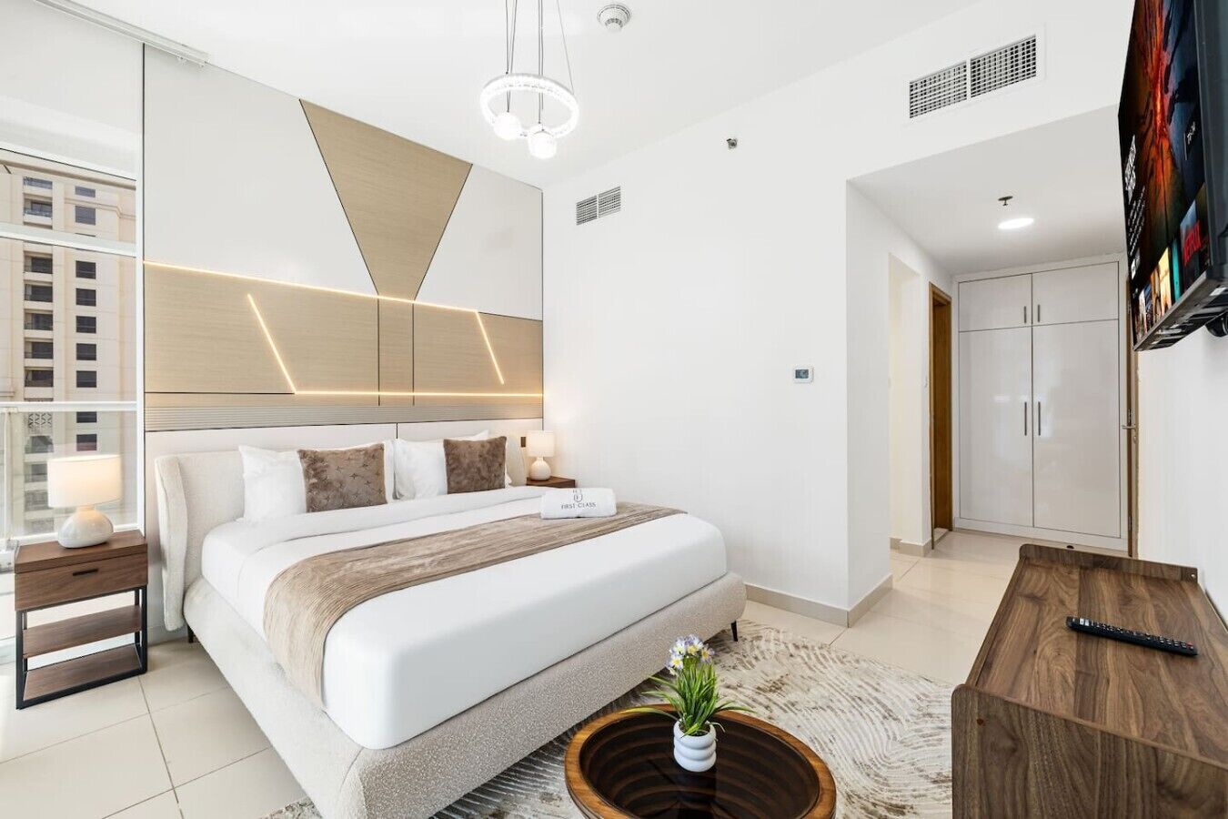Une chambre d’hôtel moderne équipée d’un grand lit, d’une table de chevet, d’une télévision et d’une armoire.