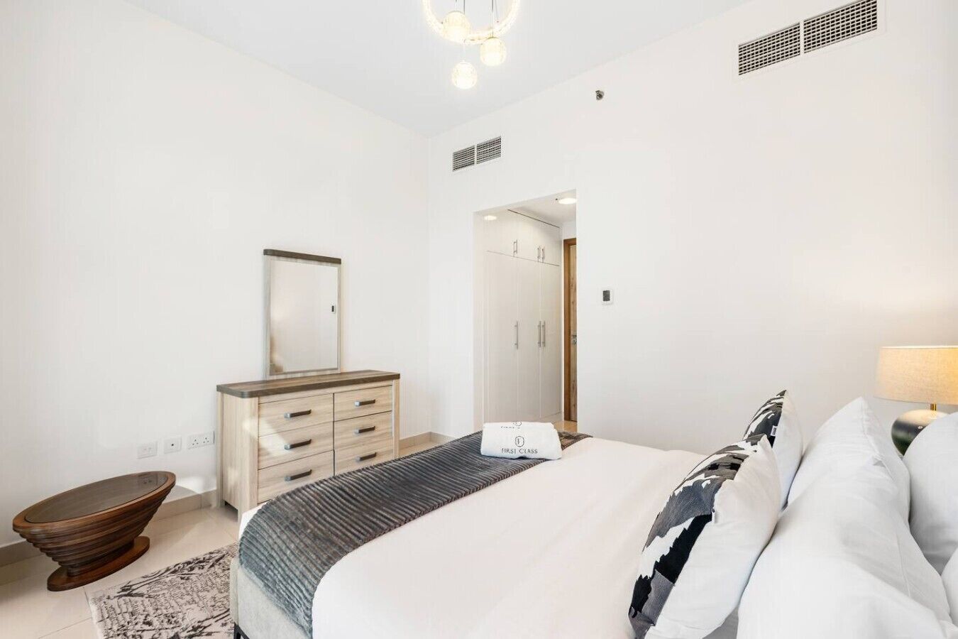 Une chambre à coucher comprenant un lit, une commode, un miroir et une porte donnant sur une autre pièce.