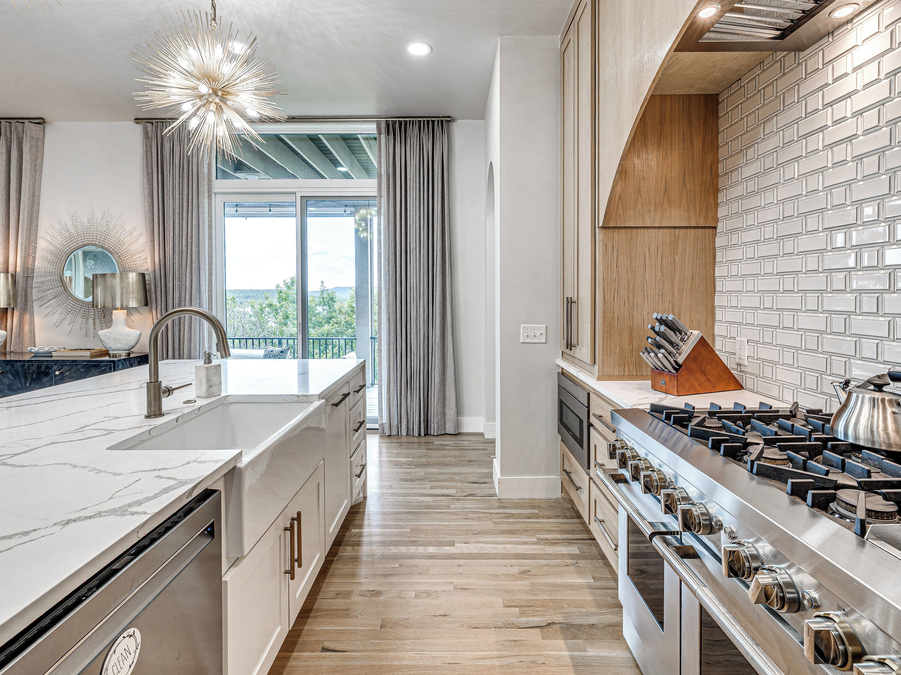 A modern kitchen with a large island, stainless steel appliances, and a view to the outdoors.