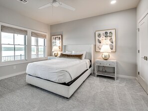 A bedroom with a bed, two bedside tables, a ceiling fan, and artwork on the walls. - Carlton Landing-Panorama (Carlton Landing)