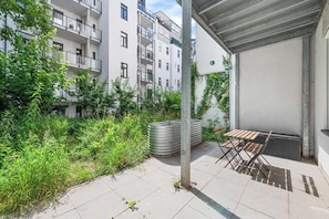 Ein Innenhof mit Tisch und Stühlen, umgeben von Pflanzen und einem Gebäude mit Balkonen.