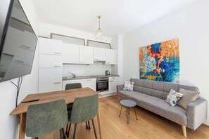 A modern living space with a dining area, kitchenette, and a large abstract painting. - Garden Retreat | Terrace | Kitchen | Center (Wien)