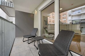 A balcony with two wicker chairs, a glass door leading to a building, and a metal railing. - AufLeeben Vienna | Kitchen | Garage | Balcony (Wien)