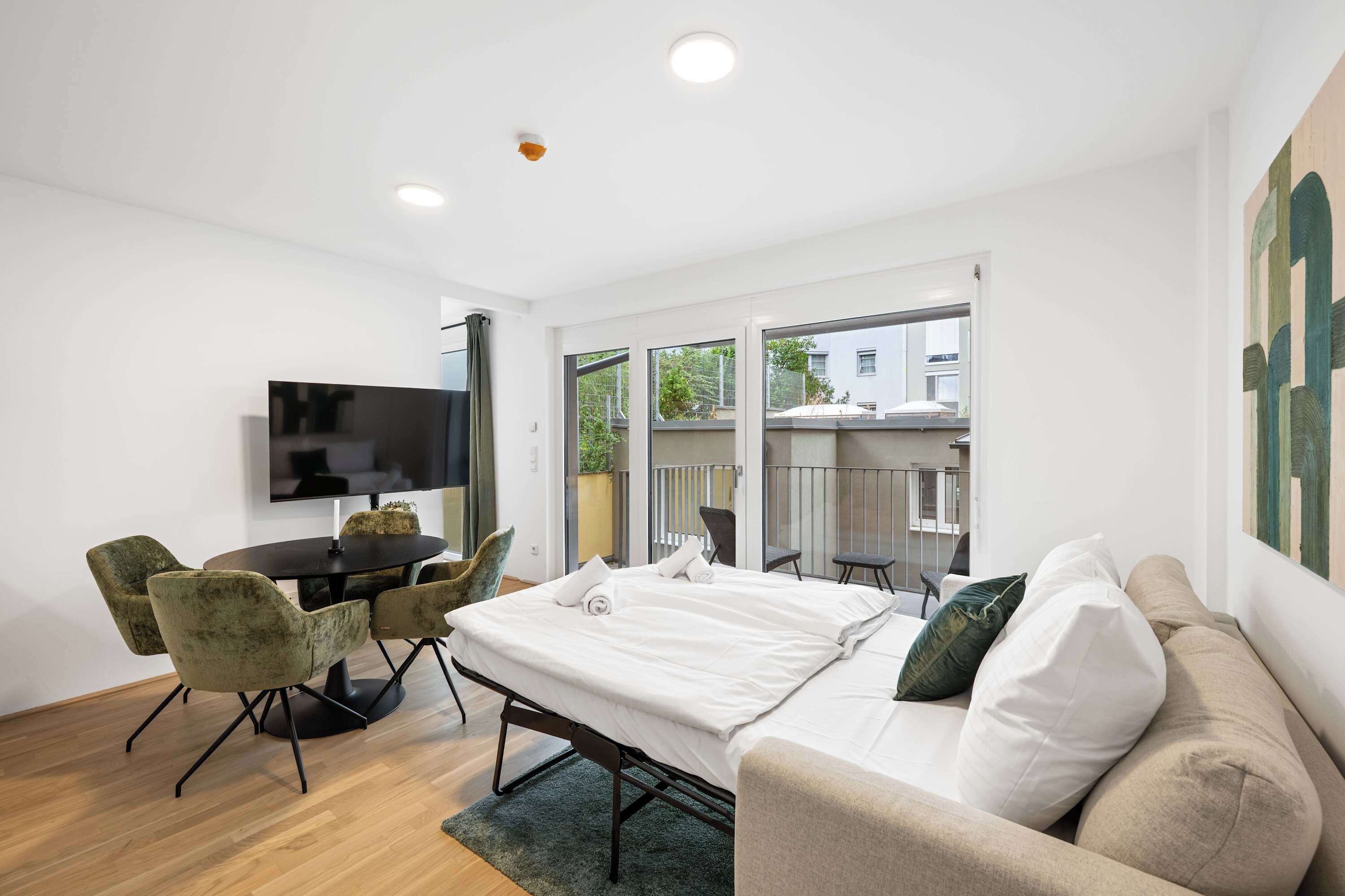 Una habitación de hotel moderna con cama, escritorio, televisor y balcón con vista a la ciudad.