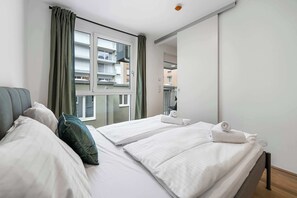 A hotel room with two beds, a large window, and a view of the city. - AufLeeben Vienna | Kitchen | Garage | Balcony (Wien)