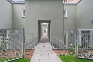 A corridor with metal railings, a tiled floor, and a clear view into the building. - AufLeeben Vienna | Kitchen | Garage | Balcony (Wien)