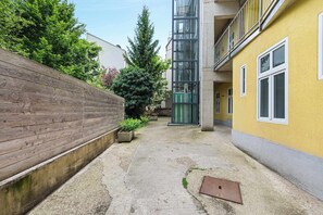 Un carrer estret amb una tanca de fusta d'un costat, una porta verda i un edifici groc de l'altre.