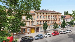 Un edificio de varios pisos con una fila de coches estacionados en la parte delantera.
