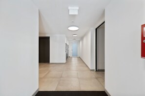 A corridor with a tiled floor, white walls, and recessed ceiling lights. - Modern Studio | King-Size | Kitchen | Metro (Wien)
